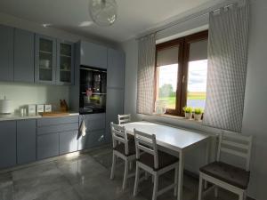 uma cozinha com uma mesa e cadeiras brancas e uma janela em Dom wakacyjny na Kaszubach em Przodkowo