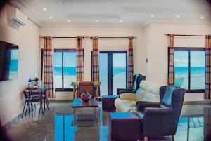 uma sala de estar com um sofá, cadeiras e janelas em Majula Boutique Hotel em Sere Kunda