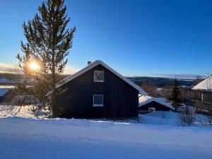 a black barn in the snow with the sun setting at House in Røros in Røros
