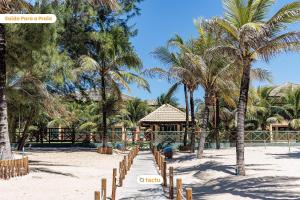 a beach with palm trees and a resort at Bangalô vista mar no VG Sun Cumbuco por Tactu in Cumbuco