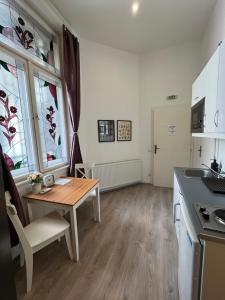 una cucina con tavolo in legno e tavolo e due finestre di D58 Delux Apartments in the city center a Budapest