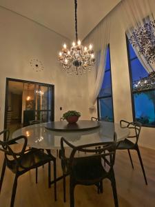 uma sala de jantar com uma mesa e cadeiras e um lustre em Casa Paradise Mogi em Mogi das Cruzes