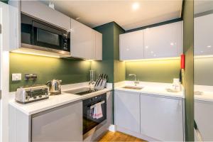 a kitchen with white cabinets and a microwave at Trendy Kings Cross Flat in London