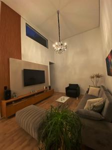 sala de estar con sofá y TV de pantalla plana en Casa Paradise Mogi, en Mogi das Cruzes