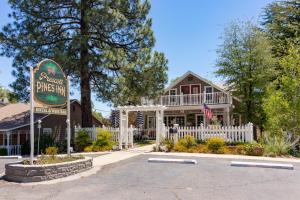 Prescott Pines Inn في بريسكوت: علامة أمام منزل به سياج