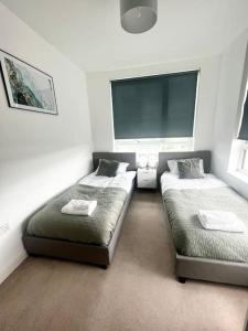 a bedroom with two beds and a large window at Modern, comfy 2 bedroom flat in Hatfield town centre in Hatfield