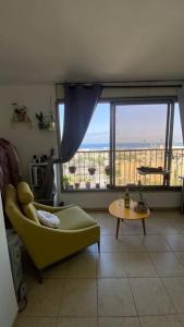 a living room with a yellow couch and a large window at Sea view apartment in Haifa