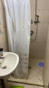 a shower with a white shower curtain next to a sink at Sea view apartment in Haifa