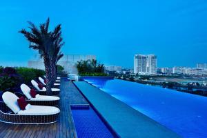 a pool with white chairs and a palm tree on a building at Courtyard by Marriott Bengaluru Hebbal in Bangalore