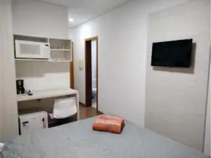 a room with a kitchen with a table and a microwave at Flats da Júnia - ótimo beneficio com wifi, ar, tv, frigobar in Lagoa Santa