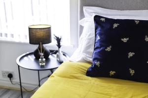 a bed with a table with a pillow with bees on it at Elegant 3 bedroom House in Leigh