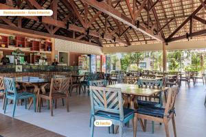 um restaurante com mesas e cadeiras de madeira e um bar em Térreo com churrasqueira no VG Sun por Tactu em Cumbuco