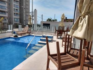 a balcony with chairs and a swimming pool on a building at Aconchegante Apto Praia do Centro in Itanhaém