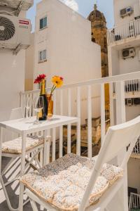 a white table and chairs on a balcony with flowers at Stylish 2BED Unit 50m from Seafront! WiFi and Washer in Il-Gżira