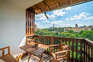 balcón con mesa de madera, sillas y vistas. en Four Riders Guest House, en Veliko Tŭrnovo