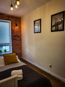 - une chambre avec un lit et un mur en briques dans l'établissement Apartament Ceglany, à Legnica