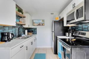 a kitchen with white cabinets and a black refrigerator at Beachside 23 in Indian Harbour Beach