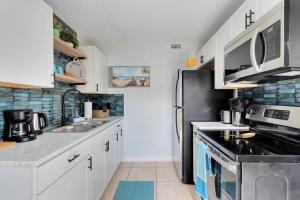 a kitchen with white cabinets and a black refrigerator at Ocean 23 - Swaying Seaweed in Indian Harbour Beach