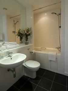 a bathroom with a toilet and a sink and a tub at Stay Deansgate Apartments for 14 nights plus in Manchester
