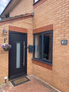 a brick building with a black door and a window at 3 bedroom home in Nottage, Porthcawl in Nottage