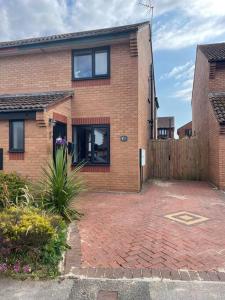 a brick house with a fence and a brick driveway at 3 bedroom home in Nottage, Porthcawl in Nottage