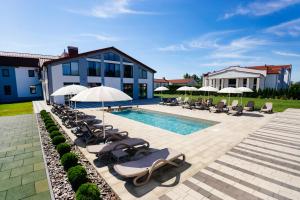 a pool with lounge chairs and umbrellas next to a building at Підгорецький маєток - готель in Pidhirtsi