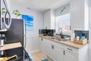 a kitchen with a sink and a refrigerator at Beachside 32 in Indian Harbour Beach