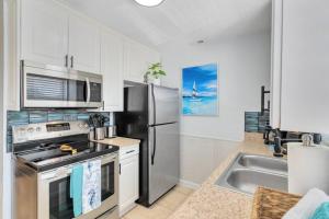 a kitchen with a stainless steel refrigerator and a sink at Beachside 32 in Indian Harbour Beach