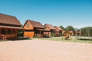 a row of wooden houses with a playground at Domki U Edzia in Kopalino