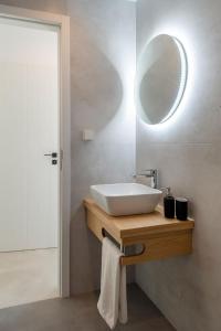 La salle de bains est pourvue d'un lavabo et d'un miroir mural. dans l'établissement Olivine Paros Villas, à Parikia