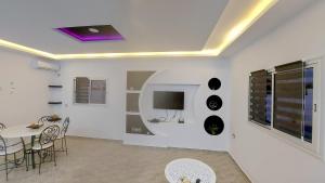 ein Wohnzimmer mit einem Tisch und einem TV an der Wand in der Unterkunft Villa kenza in Houmt Souk