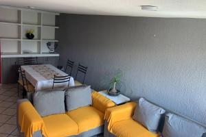una sala de estar con 2 sofás amarillos y una mesa. en casa amueblada en cuernavaca Casa Luz, en Cuernavaca