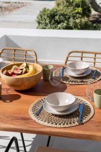 - une table en bois avec des assiettes et un bol de fruits dans l'établissement Olivine Paros Villas, à Parikia