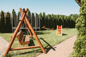 a wooden swing set in a park with trees at Domki U Edzia in Kopalino