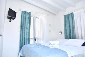 een slaapkamer met een bed met blauwe gordijnen en een televisie bij Martinos Studios in Kithnos
