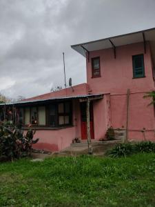 a pink house with a red door and a yard at La casa de Sibila in Bragado