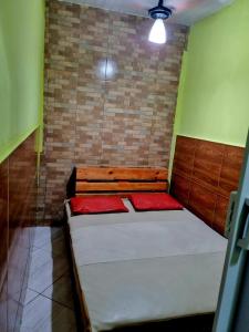 Cantinho feliz de Muriqui/ Casa verde com piscina privativa!!! في مانغاراتيبا: سرير صغير في غرفة بجدار من الطوب