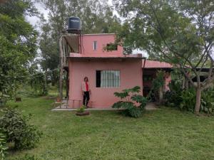 a woman standing in front of a pink house at La casa de Sibila in Bragado
