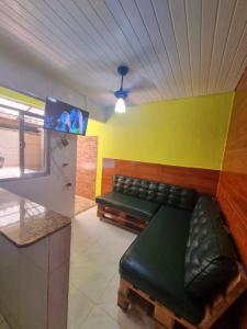 ein Wartezimmer mit einem Ledersofa und einem TV in der Unterkunft Cantinho feliz de Muriqui/ Casa verde com piscina privativa!!! in Mangaratiba