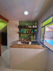 eine Küche mit einer Theke mit einem Waschbecken und einem Fenster in der Unterkunft Cantinho feliz de Muriqui/ Casa verde com piscina privativa!!! in Mangaratiba
