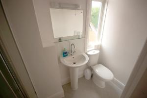 a white bathroom with a toilet and a sink at Salamander Guest House in Stratford-upon-Avon
