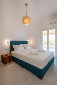 - une chambre avec un grand lit et un lustre dans l'établissement Olivine Paros Villas, à Parikia