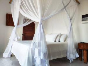 a white bed with a canopy in a bedroom at Casa do Índico in Praia do Tofo