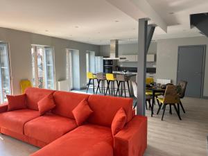 a living room with a red couch and a dining room at Le palais duplex in Autun