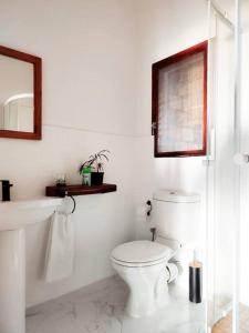 een witte badkamer met een toilet en een wastafel bij Casa do Índico in Praia do Tofo