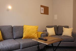 a living room with a gray couch with yellow pillows at The Arches The Wee Yin in Stirling