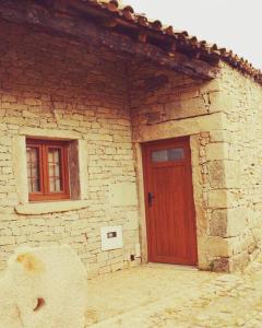 a brick building with a red door and two windows at Casa da Vila - Vilar Maior, Sabugal in Vilar Maior