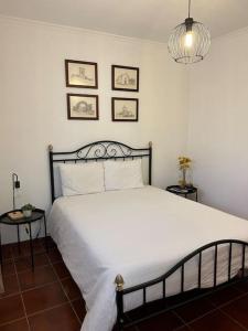 a bedroom with a large white bed and three pictures on the wall at Casa da Vila - Vilar Maior, Sabugal in Vilar Maior