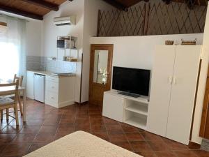 ein Wohnzimmer mit einem TV und einer Küche in der Unterkunft La mansarda di nonno Calogero in Montelepre