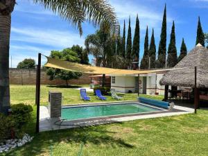 a backyard with a swimming pool with a hammock and a house at Casa de descanso alberca climatizada in Atlixco